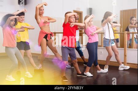 Préadolescents, garçons et filles, pratiquant la danse, s'étendant avec une entraîneuse féminine dans la salle de danse Banque D'Images