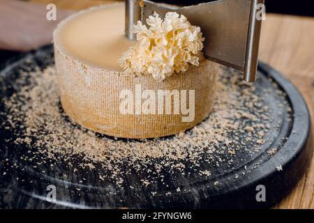 Rasage de la tête de moine à l'aide d'un couteau à girofle. Tête de moines. Variété de fromage semi-dur suisse à base de lait de vache. Banque D'Images