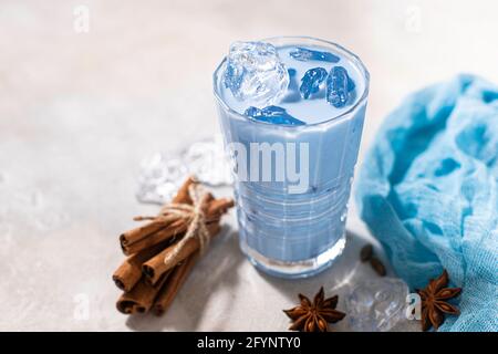Latte matcha bleu en verre sur fond de béton clair. Thé thaïlandais bleu froid avec glace et lait. Gros plan, espace de copie. Banque D'Images