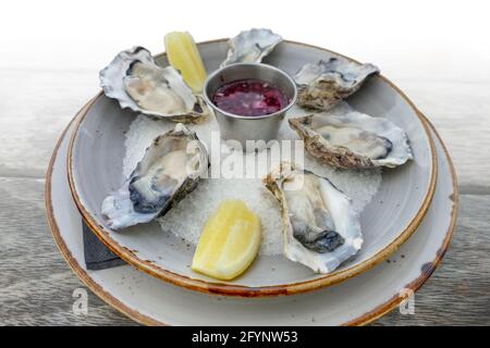 assiette avec huîtres fraîches ouvertes et trempez sur une table en bois, gradient isolé dans le dos blanc Banque D'Images