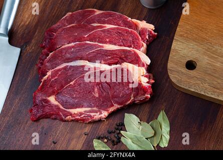 Ingrédients pour la cuisson. Entrecotes de bœuf cru avec du poivre et des feuilles de Laurier sur une surface en bois Banque D'Images