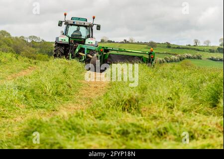 Timoleague, West Cork, Irlande. 29 mai 2021. Par un jour couvert mais sec et humide, Míchael McCarthy, qui exploite les fermes laitières avec son frère Richard, coupe un champ d'herbe pour l'ensilage avec un tracteur Deutz-Fahr Agrotron K610 et une tondeuse John Deere 1360. Crédit : AG News/Alay Live News Banque D'Images