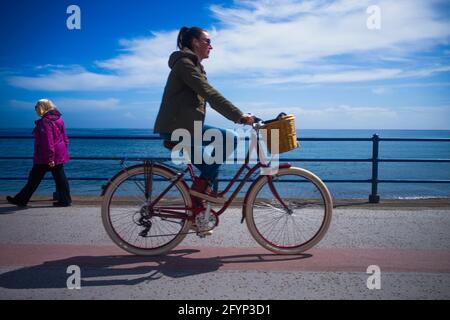 Femme âgée marchant sur le front de mer et femme cycliste à l'intérieur front avec horizon distant Banque D'Images