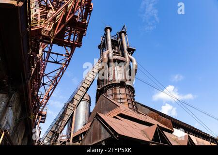 Extérieur rouillé d'un ancien complexe industriel de aciérie, formes métalliques contre un ciel bleu vif, aspect horizontal Banque D'Images