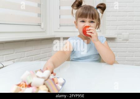 la fille mange une délicieuse tomate mûre et atteint pour des bonbons malsains. concept de sélection d'aliments sains Banque D'Images