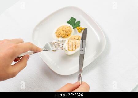 œufs farcis avec du thon en conserve et des herbes. l'homme est prêt à goûter la nourriture Banque D'Images