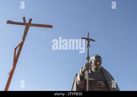 Douce contre-jour la statue du Pape Jean-Paul II et la croix moderne du grand Jésus-Criste contre le ciel bleu à Fatima, Portugal. Banque D'Images