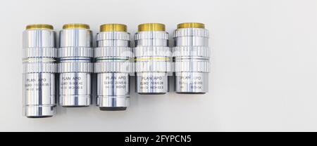 Beaucoup d'objectifs différents de l'agrandissement sur un fond blanc. Gros plan des objectifs du microscope. Banque D'Images