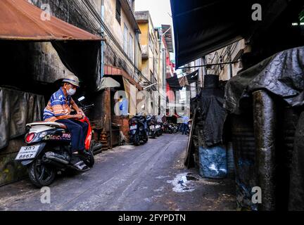 Un homme âgé est assis sur une moto dans une ruelle étroite à Talat Noi, Bangkok, Thaïlande Banque D'Images