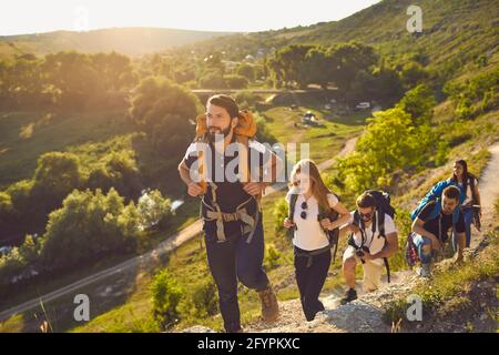 Groupe de jeunes randonneurs avec des sacs à dos sur leurs épaules marchant sur les rochers dans la campagne. Banque D'Images