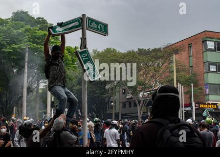 Un manifestant vandalise un panneau de rue alors que des gens protestent contre le président Ivan Duque et la brutalité policière après un mois de manifestations qui avaient fait au moins 45 morts dans des troubles et des cas d'abus de pouvoir de la police, à Medellin, Antioquia - Colombie, le 28 mai 2021. Banque D'Images