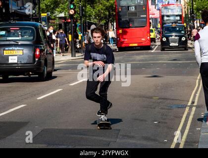 Le week-end shopping à Oxford Street à la fin du mois de mai Le soleil brille enfin et fait ressortir la foule Boy sur une planche à roulettes, au milieu de la principale Banque D'Images