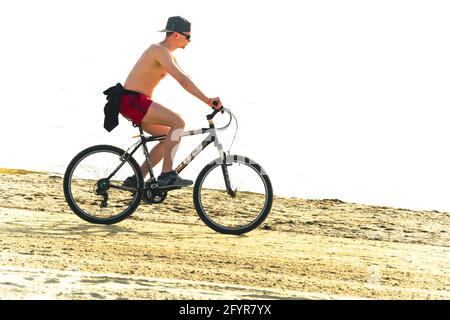 2019: le biker fait du vélo de montagne russe Stels-630 le long d'une plage de sable ensoleillé Banque D'Images