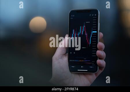 Trader regardant le téléphone mobile avec le tableau de stock à l'écran Banque D'Images