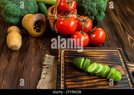 Concombre frais coupé en tranches sur la planche à découper. Préparer les ingrédients pour la salade. Légumes frais sur table. Produits agricoles biologiques. Brocoli, tomatoe Banque D'Images