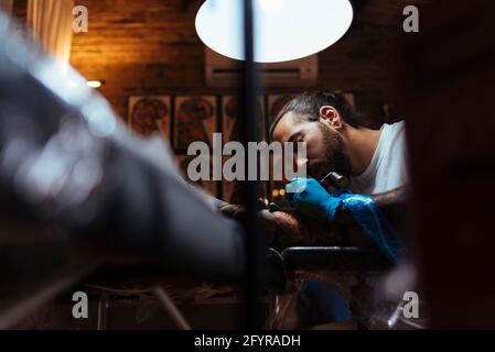 Voir sous de tatouage artiste travaillant avec un client dans son studio. Banque D'Images