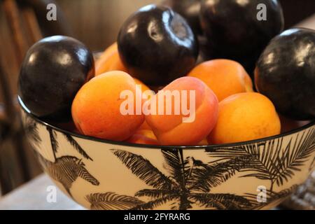 Vase avec abricots frais et prunes ambrées noires dans la cuisine Banque D'Images