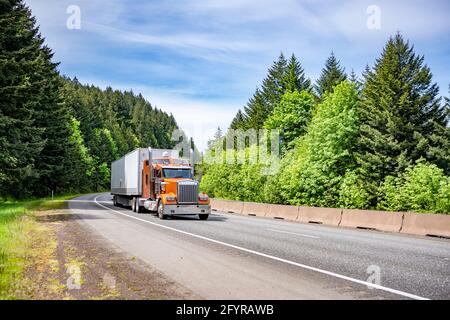 Tracteur semi-remorque Orange Big RIG American idol avec chrome des accessoires en un clin d'œil pour une livraison rapide des marchandises chargées en camionnette sèche semi-remorque en marche Banque D'Images