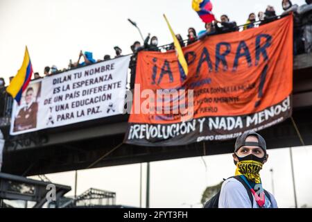 Un protestataires avec son visage couvert, debout sous le pont où pendent des banderoles antigouvernementales sur la Plaza de Los Heroes (place Heros). L'un d'eux commémore la mort de Dilan Cruz, un jeune garçon tué par la police en 2019 pendant la manifestation.le 28 mai, un mois après le début de la grève nationale, les manifestants continuent de manifester dans les rues de Bogotá et dans tout le pays pour s'opposer aux politiques gouvernementales. Dans la capitale, plusieurs manifestations et marches ont eu lieu pendant la journée, avec des milliers de personnes participant à la grève. Sur la Plaza de Los Heroes (Heros Banque D'Images