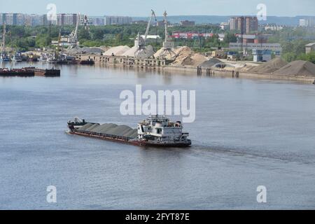 Le remorqueur transporte une barge chargée de sable le long de la rivière. Banque D'Images