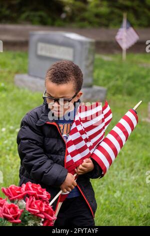 Bloomington, États-Unis. 29 mai 2021. Dominic Harris, de Cub Scouts pack 145, cherche des sites donnés tout en portant des drapeaux américains qui sont placés au cimetière de Rose Hill pour le Memorial Day samedi. Le Memorial Day, qui est le lundi 31 mai de cette année, est une fête fédérale pour honorer les membres des Forces armées des États-Unis qui sont morts dans l'exercice de leurs fonctions. Crédit : SOPA Images Limited/Alamy Live News Banque D'Images