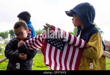 Bloomington, États-Unis. 29 mai 2021. Dominic Harris, Grayson Buchanan et Damon Harris aident à placer des drapeaux américains sur les tombes d'anciens combattants du cimetière de Rose Hill pour le Memorial Day Saturday. Le Memorial Day, qui est le lundi 31 mai de cette année, est une fête fédérale pour honorer les membres des Forces armées des États-Unis qui sont morts dans l'exercice de leurs fonctions. Crédit : SOPA Images Limited/Alamy Live News Banque D'Images