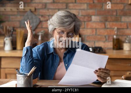 Une femme âgée excitée lisant des nouvelles fantastiques dans la lettre postale Banque D'Images