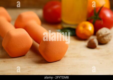 Haltères, jus d'orange, fruits et noix sur la table en bois, sport et santé concept de style de vie Banque D'Images