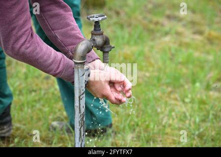 Un ouvrier en combinaison de travail lave ses mains au-dessus de l'eau à natur Banque D'Images