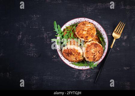 Dîner sain. Côtelettes de poulet dans un bol sur fond sombre. Vue de dessus, plan d'appartement Banque D'Images
