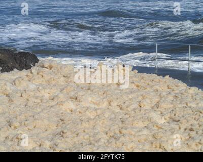 Une épaisse couche de mousse sale de mer s'est formée pendant un certain temps avec de forts vents et de grands vagues, couvrant presque totalement la piscine de roche. Australie Banque D'Images