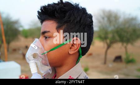 Un petit garçon qui respire avec un masque à oxygène à la maison. Enfant indien malade infecté par la maladie de Covid 19. Garçon indien prenant traitement de l'asthme, poumons. Banque D'Images