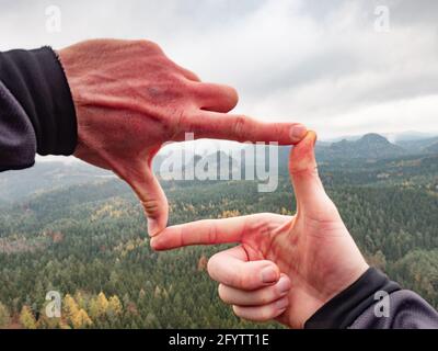 Homme regardant le paysage vallonné cadrage avec les doigts, à la recherche de la composition d'image pendant qu'il randonnée au-dessus de la chaîne de montagne. Photographe paysagiste Banque D'Images