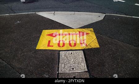 Panneau jaune et rouge avec flèches peintes sur le pavé à Brisbane, Australie Banque D'Images