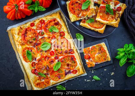 Tarte végétarienne aux tomates ou pizza soufflée aux herbes sur le noir arrière-plan Banque D'Images