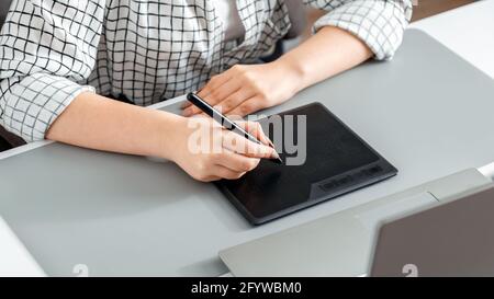 Créateur travaillant avec des équipements professionnels. Le stylet dessine sur la tablette graphique. Une femme de créateur, éditeur ou photographe, utilise une tablette graphique Banque D'Images