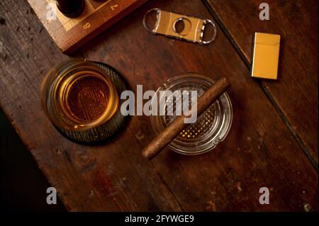 Cigare dans cendrier, alcool, allume-cigare et guillotine Banque D'Images