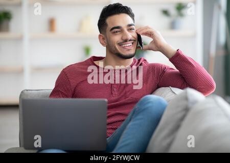 Un homme arabe positif ayant une conversation téléphonique à la maison Banque D'Images