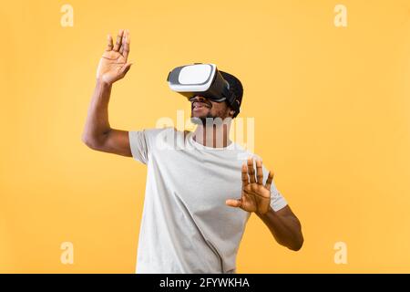 Une technologie et un monde virtuel exceptionnels dans la simulation 3D. Homme afro-américain en verres vr sur fond jaune Banque D'Images