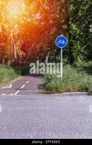 indication d'une piste cyclable par un panneau à un carrefour dans un grand parc boisé par une journée ensoleillée Banque D'Images