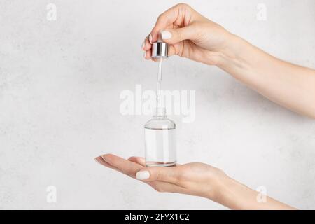 main d'une jeune femme qui goutte un hydratant au collagène à l'aide d'une pipette. Arrière-plan blanc. Image horizontale. Espace de copie Banque D'Images