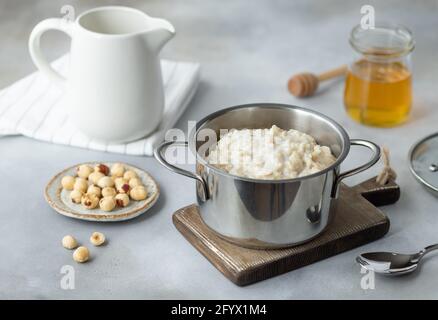 faites une casserole avec du porridge de flocons d'avoine maison, du miel et des noix sur la table grise. Petit déjeuner chaud et sain. Image horizontale. Banque D'Images