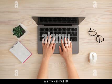 Concept d'espace de travail. Les femmes travaillent sur le bureau, tapant sur le clavier de l'ordinateur portable, vue du dessus Banque D'Images