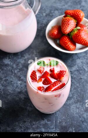 Yaourt à la fraise avec baies fraîches en verre sur fond de pierre bleue. Concept de nourriture et de boisson saine. Banque D'Images