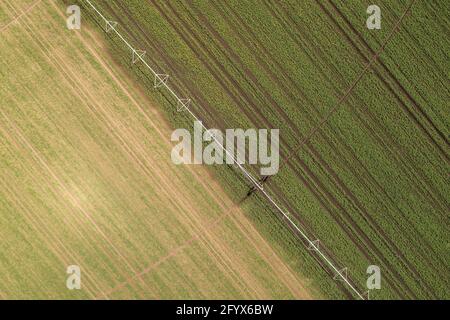 Vue aérienne de l'équipement d'irrigation à pivot central arrosant des semis de soja vert sur une plantation agricole, images de drone pov Banque D'Images