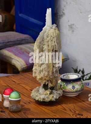 Plusieurs bougies fondues forment des stalactites de cire, sur une table devant un restaurant dans la ville marocaine d'Essaouira, en Afrique du Nord. Banque D'Images