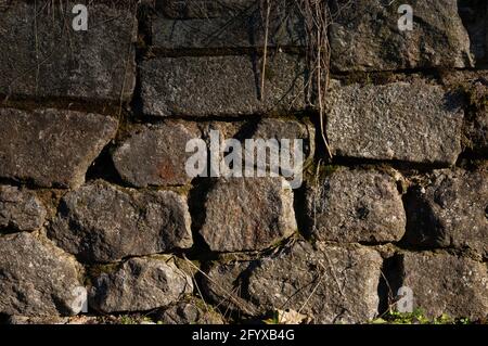 un mur de pierres de granit rugueuses, avec de la mousse dans les fissures Banque D'Images