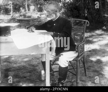 Le comte général japonais Nogi Maresuke (1849 - 1912) assis à une table pour étudier une carte au quartier général japonais pendant la guerre russo-japonaise, Port Arthur, Chine, 1904. (Photo de Burton Holmes) Banque D'Images