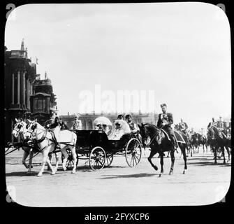 Le tsar russe Nicholas II (1868 - 1918) à côté d'une calèche transportant son épouse, la russe Tsarina Alexandra Feodorovna d'origine allemande, également connue sous le nom d'Alix de Hesse, (1872 - 1918) mère, l'impératrice danoise Maria Feodorovna (1847 - 1928) et sœur, la Grande Duchesse russe Olga Alexandrovna (1882 - 1960) Défilé du Palais d'hiver, Saint-Pétersbourg, Russie, 1901. Le cortège impérial se déplace vers un examen des troupes. (Photo de Burton Holmes) Banque D'Images