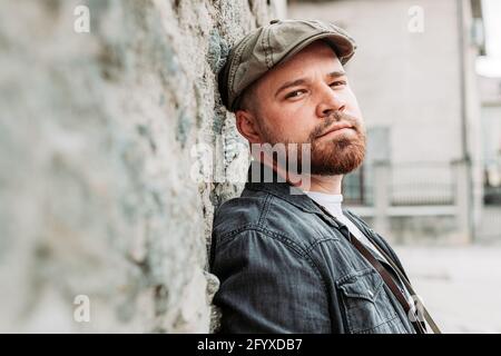 Portrait d'un beau gars avec un chapeau de lierre appuyé sur le mur, souriant Banque D'Images